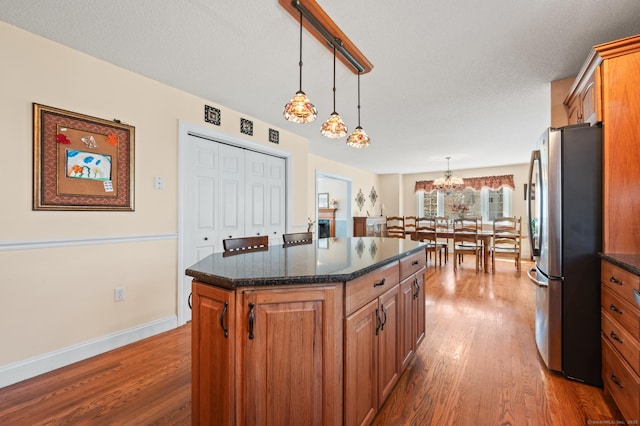 kitchen featuring dark wood-type flooring, brown cabinetry, and freestanding refrigerator