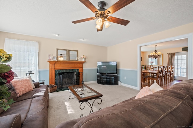 carpeted living room with ceiling fan with notable chandelier, a premium fireplace, a textured ceiling, and baseboards