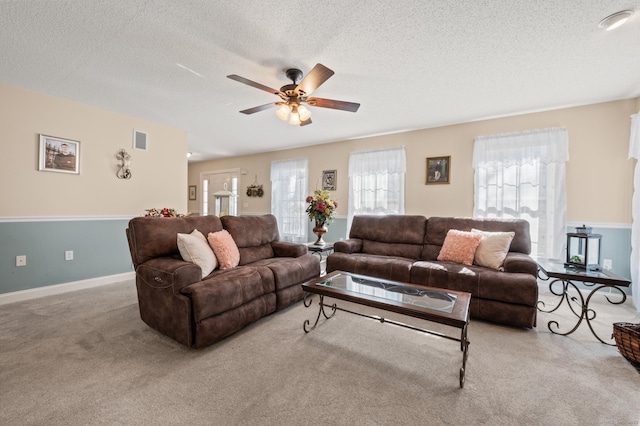 living area with ceiling fan, visible vents, and a textured ceiling