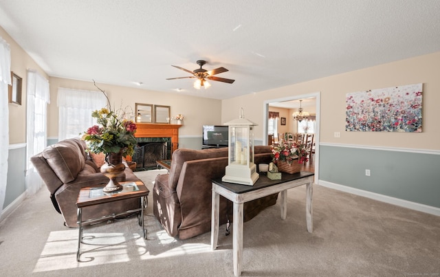 living area featuring a textured ceiling, ceiling fan with notable chandelier, carpet floors, a premium fireplace, and baseboards