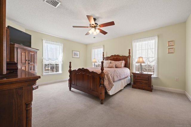 carpeted bedroom with a textured ceiling, multiple windows, and visible vents