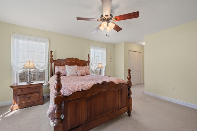 bedroom with baseboards, a closet, and light colored carpet