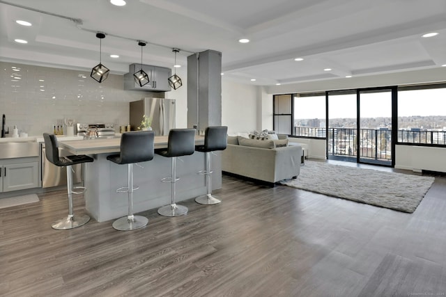 bar with a tray ceiling, dark wood-style flooring, recessed lighting, freestanding refrigerator, and a sink