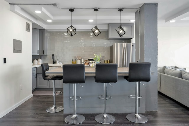 bar with recessed lighting, visible vents, backsplash, freestanding refrigerator, and dark wood-style floors