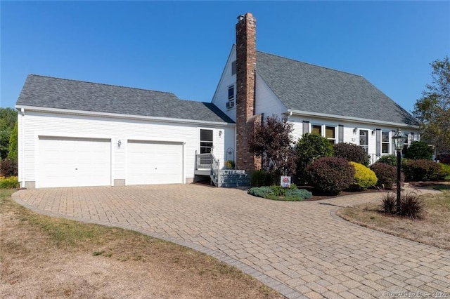 view of front of home with an attached garage, a chimney, decorative driveway, and roof with shingles