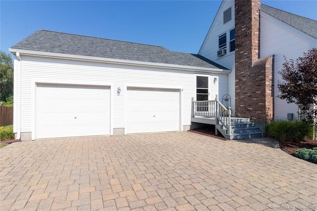 view of front of house featuring a garage, roof with shingles, and decorative driveway