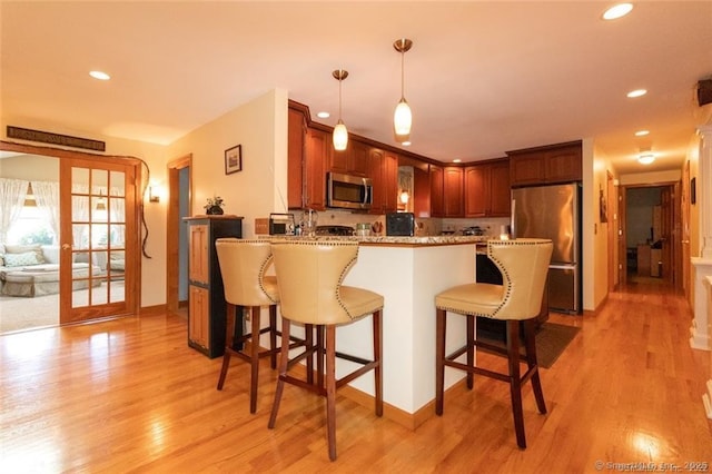 kitchen featuring a peninsula, light wood finished floors, a breakfast bar area, and stainless steel appliances