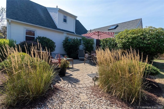 rear view of property featuring a patio area and roof with shingles