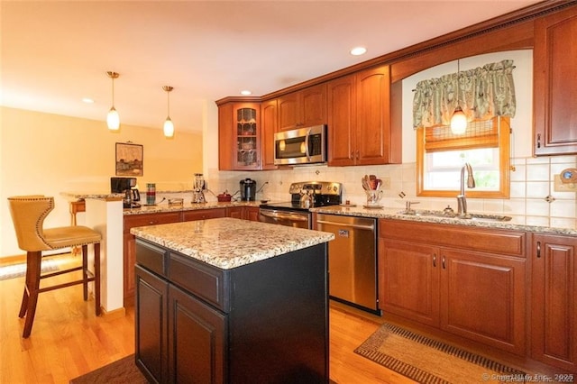 kitchen with light wood-type flooring, tasteful backsplash, stainless steel appliances, and a sink