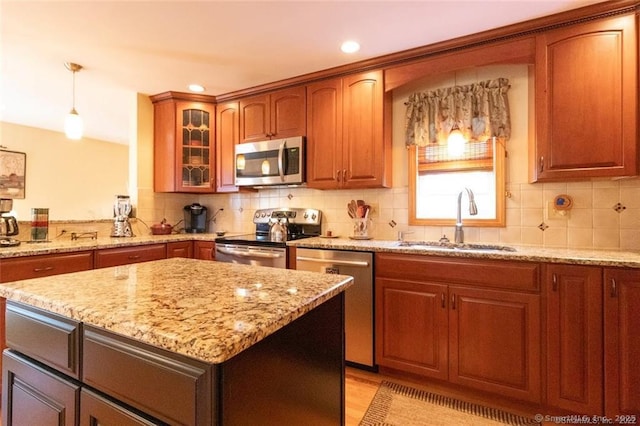 kitchen with stainless steel appliances, a sink, decorative backsplash, and light stone counters