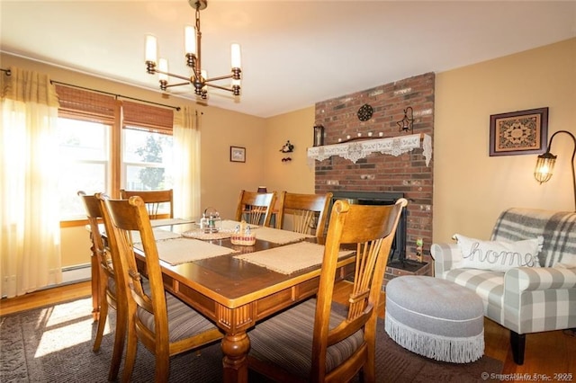 dining area featuring a fireplace, a chandelier, and wood finished floors