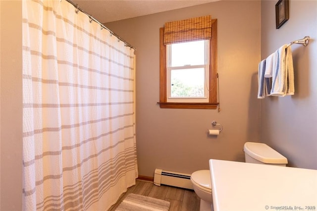 bathroom with toilet, baseboard heating, wood finished floors, a shower with curtain, and baseboards