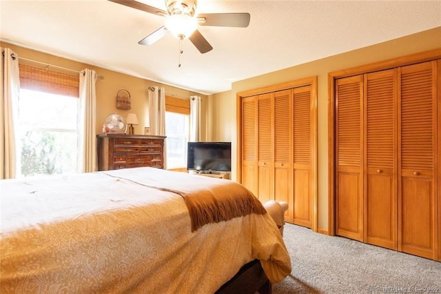 carpeted bedroom with a ceiling fan and two closets