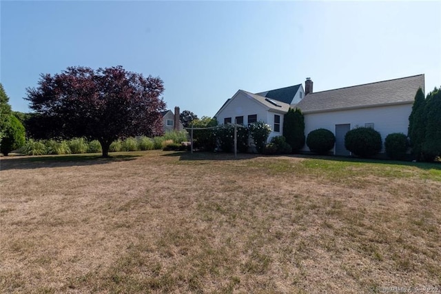 view of side of home featuring a chimney and a lawn