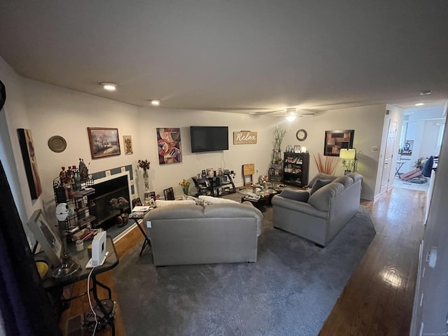 living room with a fireplace, a ceiling fan, and wood finished floors