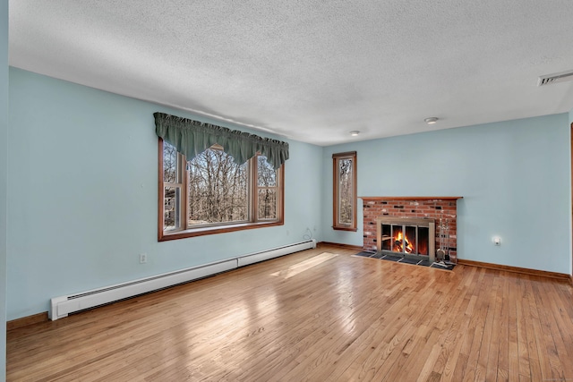 unfurnished living room with hardwood / wood-style flooring, a baseboard radiator, a fireplace, and visible vents