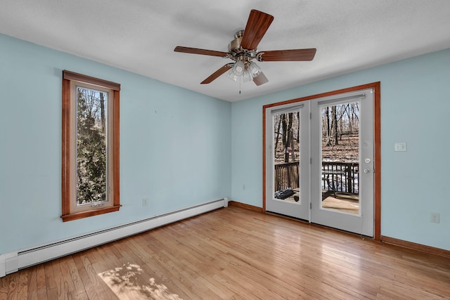 spare room featuring light wood-style floors, baseboards, a baseboard heating unit, and a ceiling fan