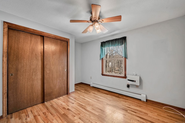 unfurnished bedroom featuring a textured ceiling, a baseboard radiator, a ceiling fan, a closet, and light wood finished floors