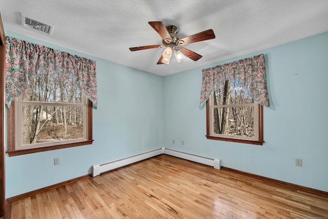 unfurnished room with a baseboard radiator, visible vents, ceiling fan, and wood finished floors