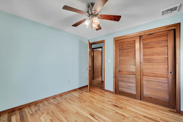 unfurnished bedroom with light wood finished floors, baseboards, visible vents, a ceiling fan, and a closet