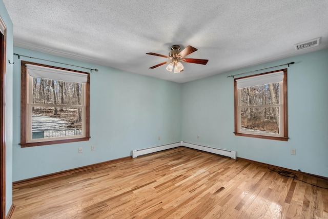 spare room featuring visible vents, a baseboard heating unit, ceiling fan, a textured ceiling, and wood finished floors