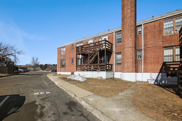 view of building exterior with stairs and uncovered parking