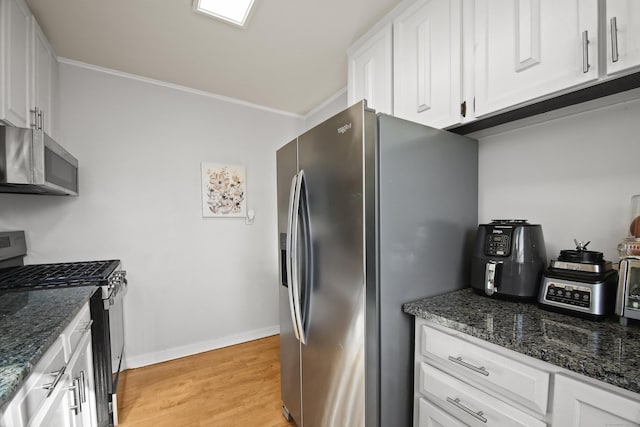 kitchen with stainless steel appliances, baseboards, white cabinets, light wood finished floors, and dark stone countertops