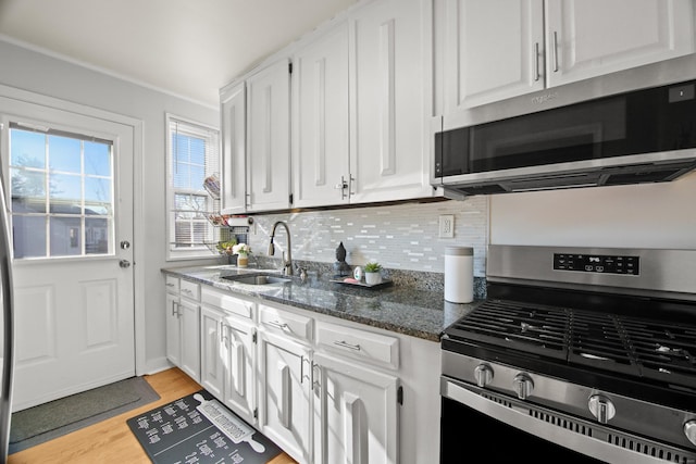 kitchen with stainless steel appliances, decorative backsplash, a sink, and white cabinets