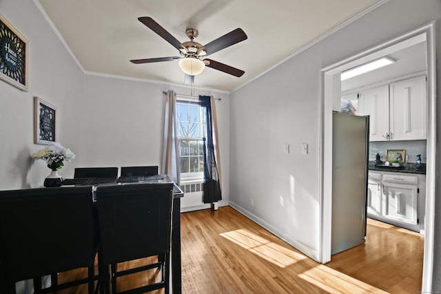 dining room featuring light wood-type flooring, baseboards, ornamental molding, and ceiling fan