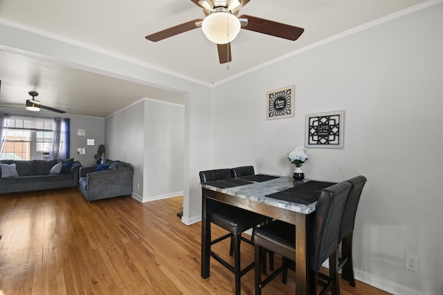 dining room featuring light wood-style floors, ornamental molding, baseboards, and a ceiling fan