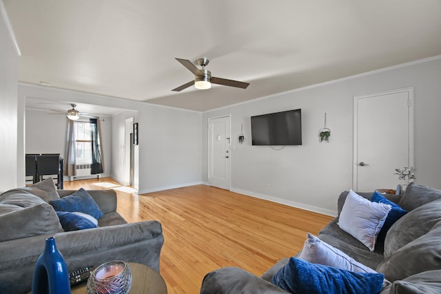 living area featuring baseboards, ceiling fan, crown molding, and light wood-style floors