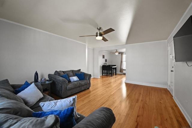 living area with baseboards, crown molding, and light wood finished floors