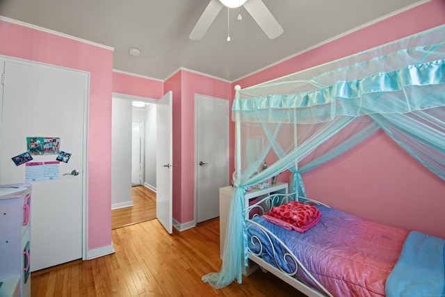 bedroom with a ceiling fan, wood-type flooring, crown molding, and baseboards