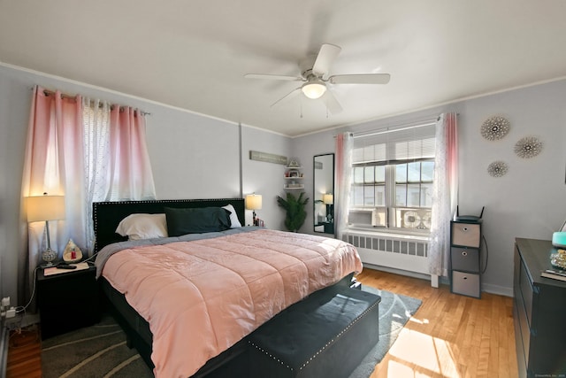 bedroom with light wood-style floors, radiator, and ceiling fan