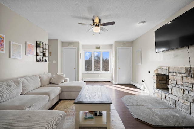 living area featuring wood finished floors, a baseboard radiator, a fireplace, ceiling fan, and a textured ceiling