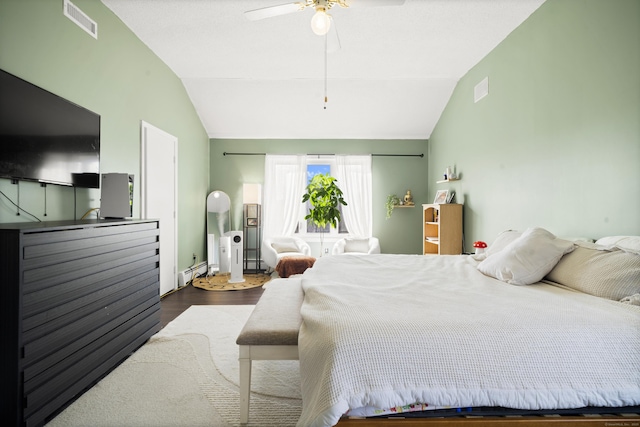 bedroom with a baseboard heating unit, visible vents, wood finished floors, and vaulted ceiling