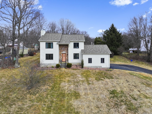 view of front of house with stone siding, a chimney, and a shingled roof