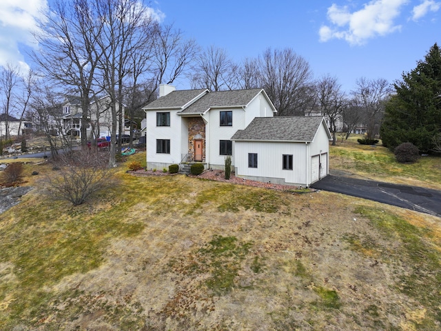 view of front facade featuring aphalt driveway, a chimney, a garage, and roof with shingles