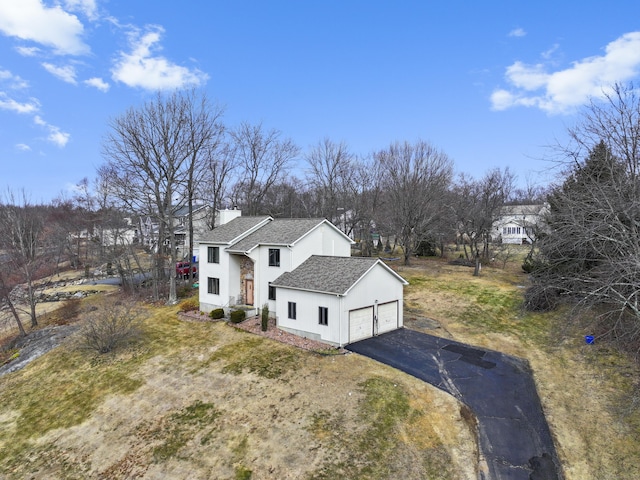 view of front of home featuring driveway, a chimney, an attached garage, and roof with shingles