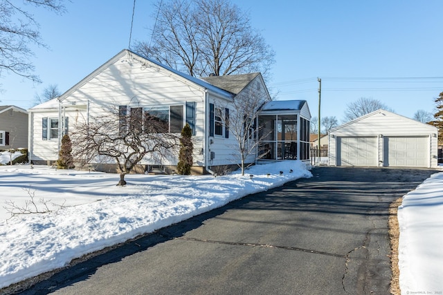 bungalow-style house featuring an outbuilding, a sunroom, and a detached garage