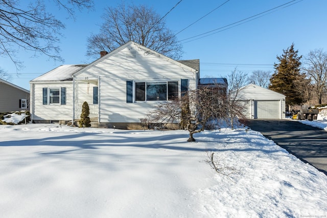 view of front of house with a garage, driveway, a chimney, and an outbuilding