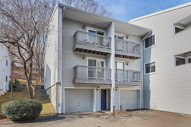 back of house featuring a garage, central AC unit, and aphalt driveway