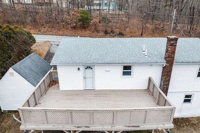 rear view of house featuring a deck, roof with shingles, and a chimney