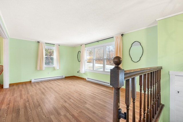 unfurnished room featuring a baseboard radiator, wood finished floors, and a wealth of natural light