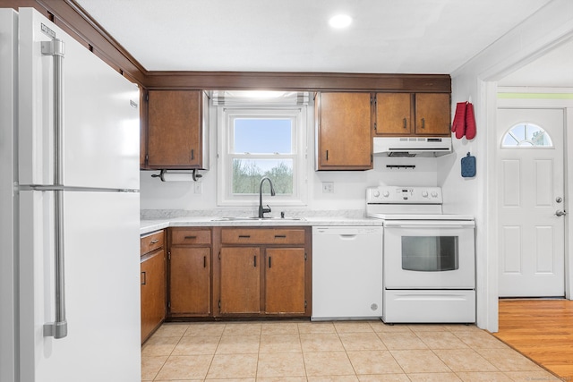 kitchen with white appliances, brown cabinetry, extractor fan, light countertops, and a sink