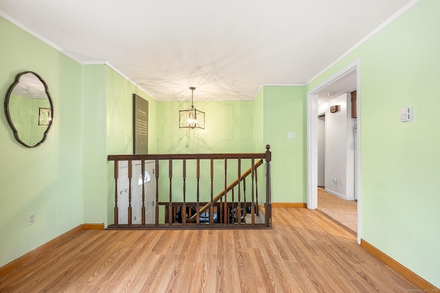 unfurnished room with crown molding, a notable chandelier, baseboards, and wood finished floors