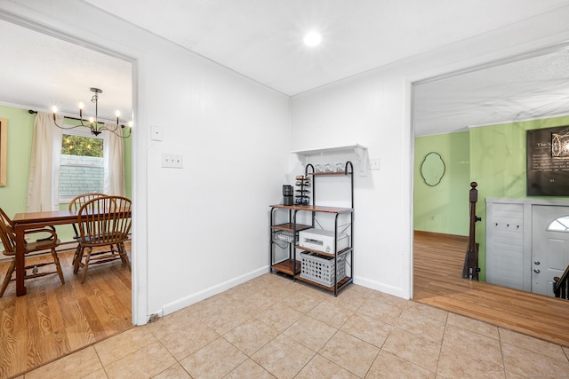 corridor with crown molding, baseboards, tile patterned flooring, and a notable chandelier