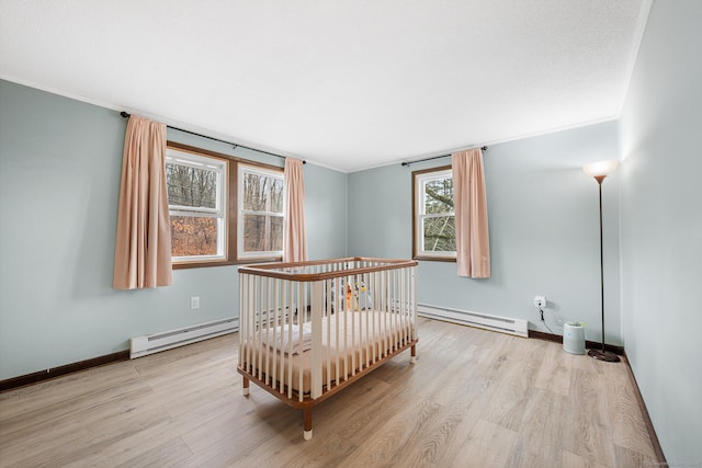 bedroom featuring crown molding, baseboard heating, wood finished floors, and baseboards