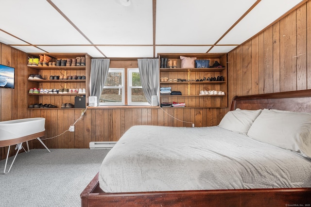 bedroom featuring carpet, wood walls, and baseboard heating