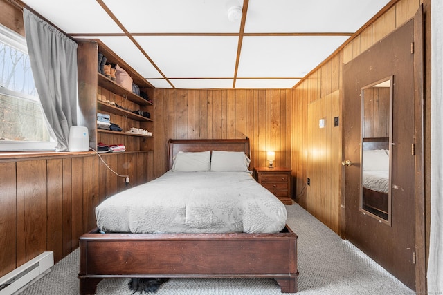 carpeted bedroom with wood walls and a baseboard heating unit